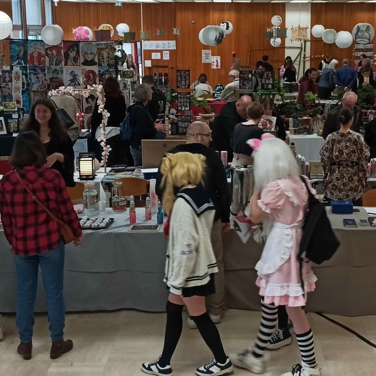 Photo d'une des allées du festival Kitsune du 18 mai 2024 où l'on voit des passionnées du Japon en cosplay et des exposants en arrière plan.