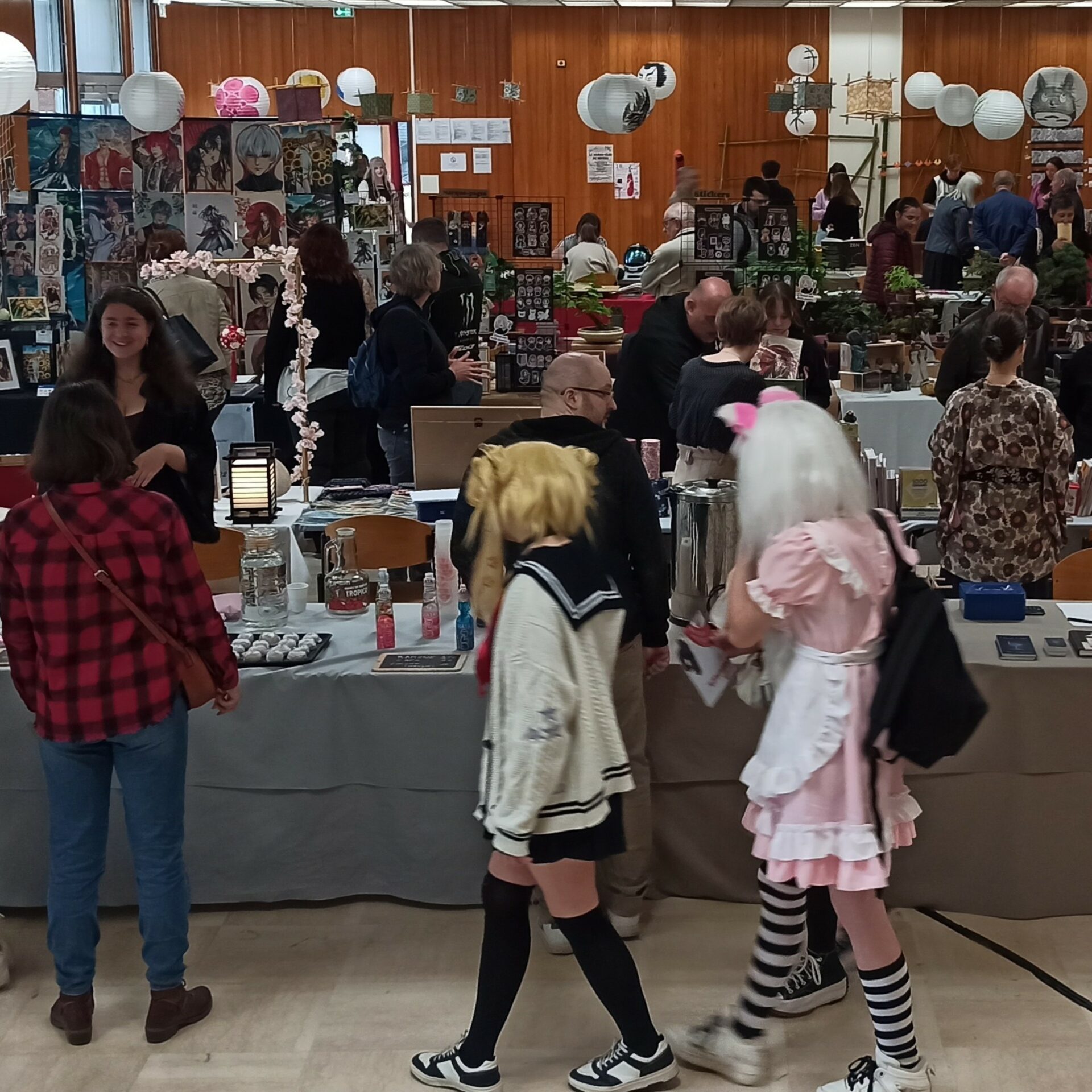 Photo d'une des allées du festival Kitsune du 18 mai 2024 où l'on voit des passionnées du Japon en cosplay et des exposants en arrière plan.